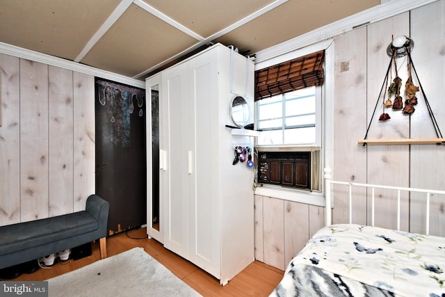 bedroom with wooden walls and light wood-type flooring