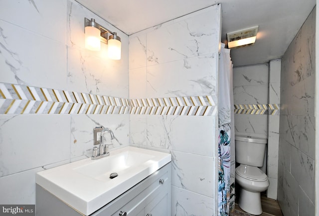 bathroom with vanity, toilet, and tile walls