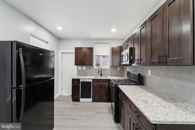 kitchen with sink, backsplash, black appliances, dark brown cabinets, and light wood-type flooring