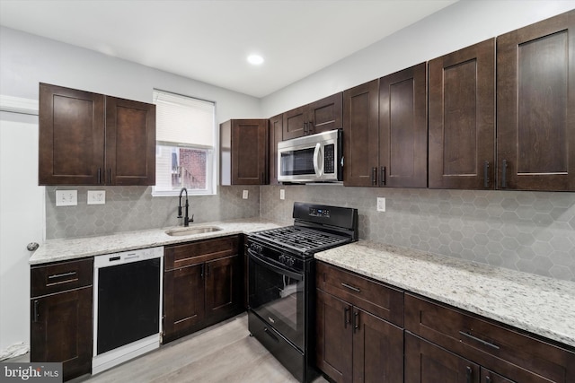 kitchen featuring tasteful backsplash, light stone countertops, sink, and black appliances