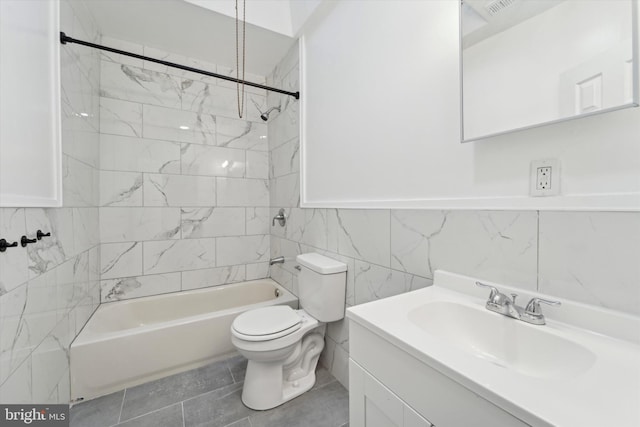 full bathroom with tiled shower / bath, tile walls, tile patterned flooring, vanity, and toilet