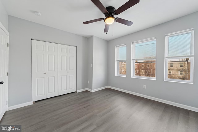 unfurnished bedroom with multiple windows, ceiling fan, dark hardwood / wood-style flooring, and a closet