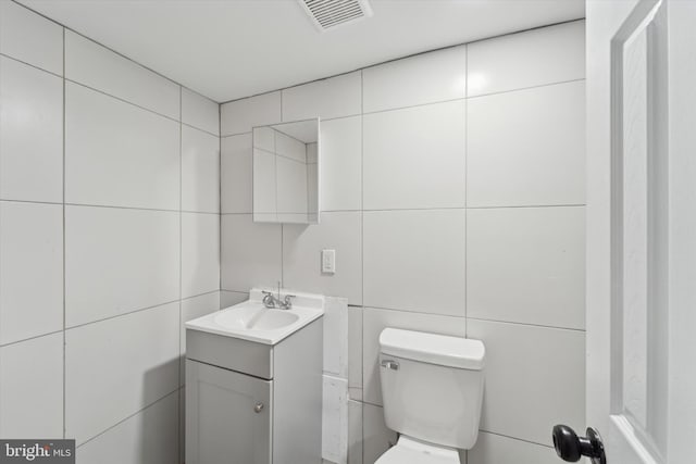 bathroom with vanity, tile walls, and toilet