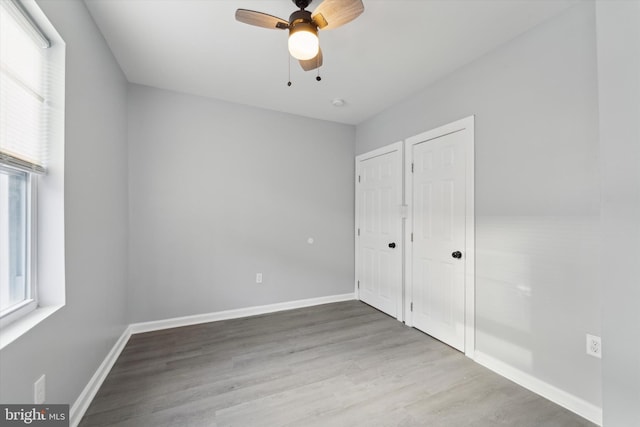 unfurnished bedroom with hardwood / wood-style flooring, two closets, and ceiling fan