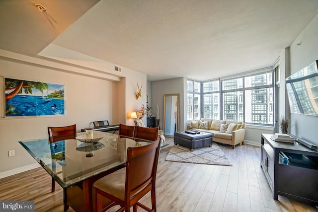 dining room featuring light hardwood / wood-style flooring and a textured ceiling