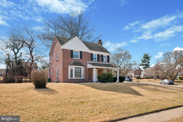 view of front facade featuring a front yard, brick siding, and a chimney