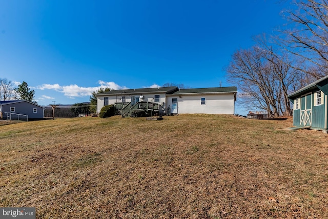 back of property with a wooden deck and a lawn