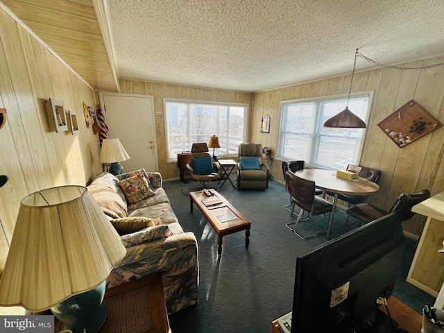 carpeted living room featuring wooden walls and a textured ceiling