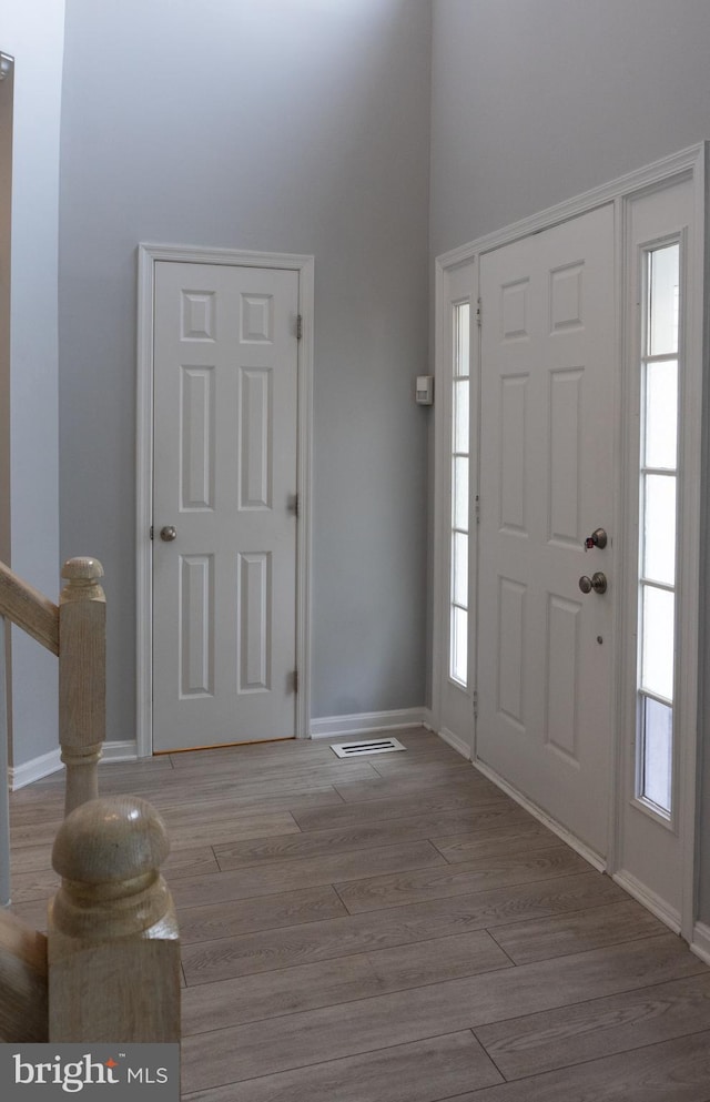 foyer featuring baseboards, visible vents, and wood finished floors