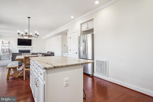 kitchen featuring white cabinetry, light stone counters, a center island, stainless steel refrigerator, and dark hardwood / wood-style floors