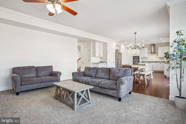 carpeted living room with ornamental molding and ceiling fan with notable chandelier