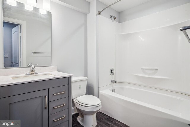 full bathroom with vanity, hardwood / wood-style floors, shower / washtub combination, and toilet