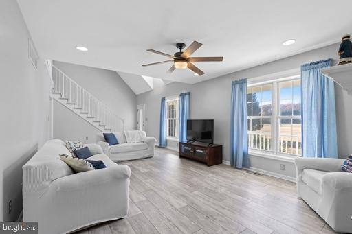 living room featuring ceiling fan, vaulted ceiling, and light wood-type flooring