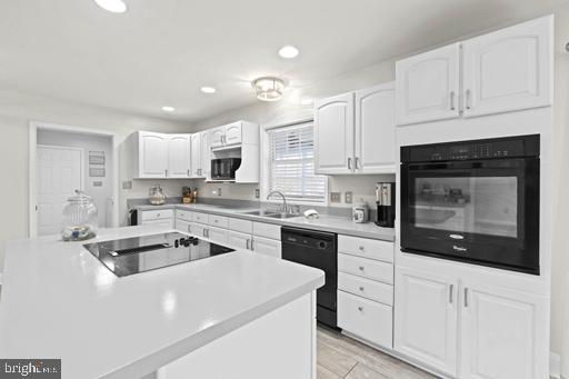 kitchen with white cabinetry, sink, and black appliances