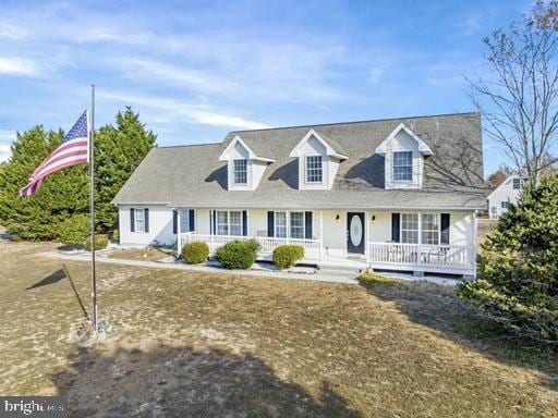 cape cod house with covered porch and a front yard