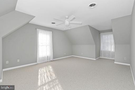 additional living space with vaulted ceiling, light carpet, and ceiling fan