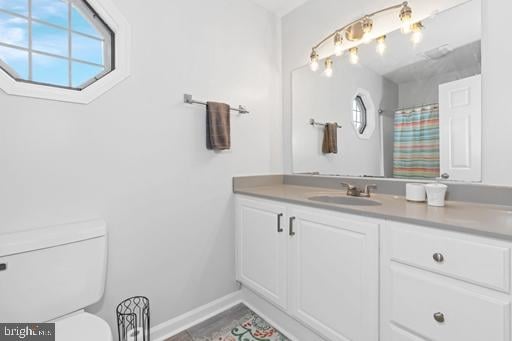 bathroom featuring vanity, curtained shower, and toilet