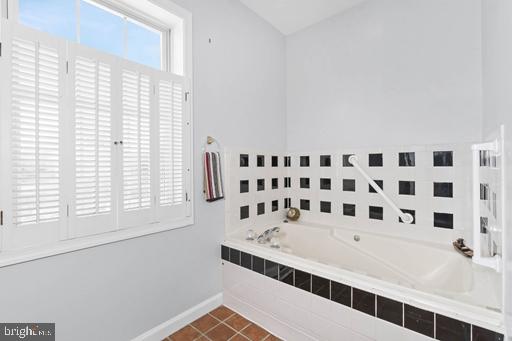 bathroom featuring tile patterned flooring and a relaxing tiled tub