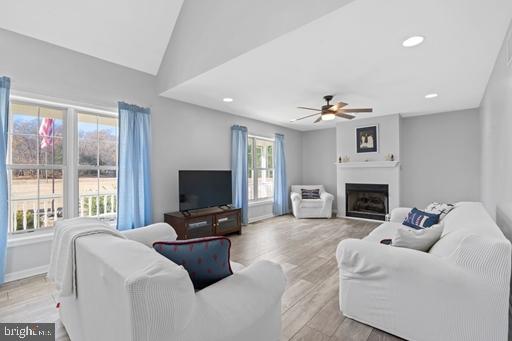 living room with ceiling fan, lofted ceiling, and light hardwood / wood-style flooring