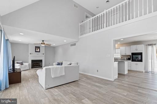 living room featuring ceiling fan, light hardwood / wood-style flooring, and a high ceiling