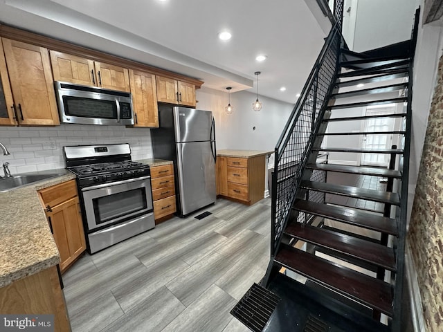 kitchen featuring sink, decorative backsplash, stainless steel appliances, and hanging light fixtures