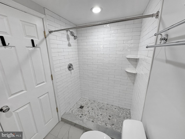 bathroom with tiled shower and toilet