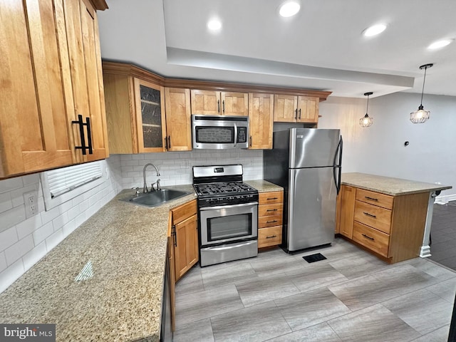 kitchen featuring pendant lighting, tasteful backsplash, sink, stainless steel appliances, and light stone countertops