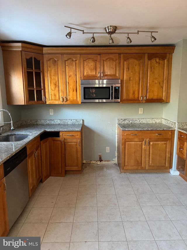 kitchen with appliances with stainless steel finishes, rail lighting, sink, light tile patterned floors, and light stone countertops