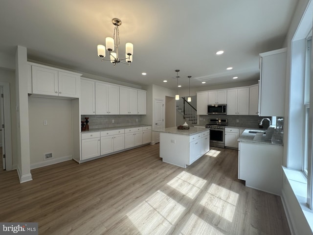 kitchen featuring pendant lighting, sink, white cabinetry, stainless steel appliances, and a center island