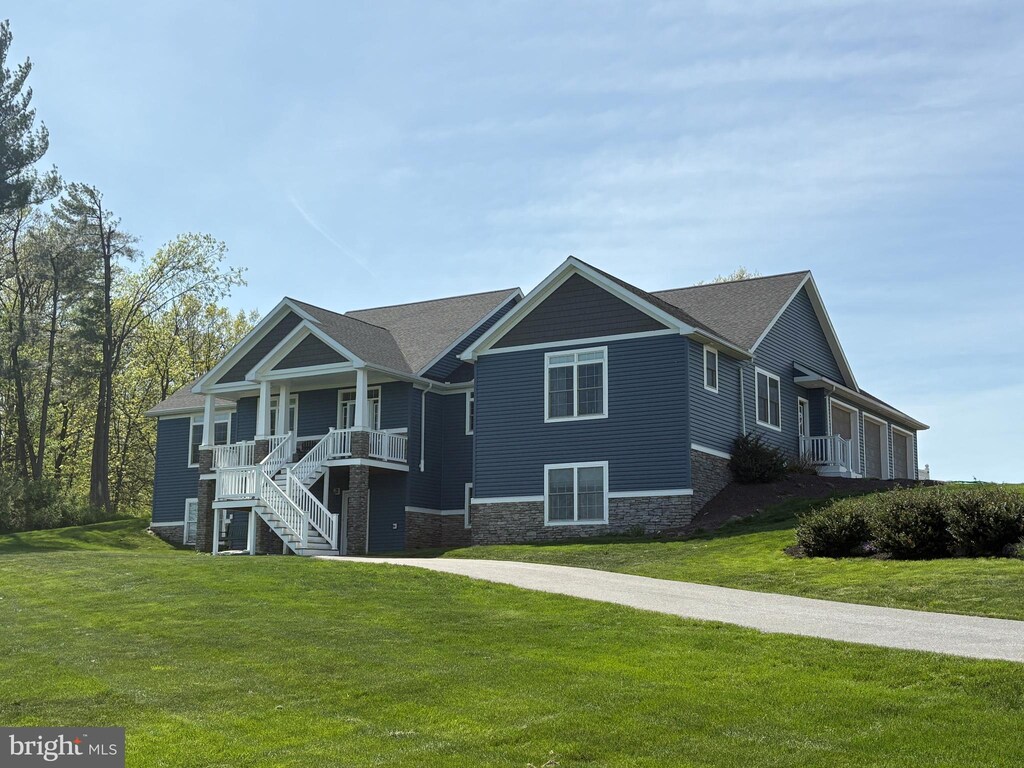 view of front of house with a front lawn, a porch, stairway, and stone siding