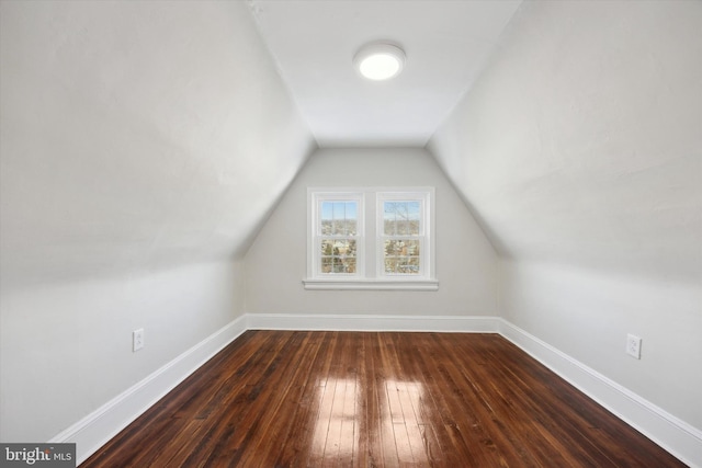 additional living space featuring vaulted ceiling and dark wood-type flooring