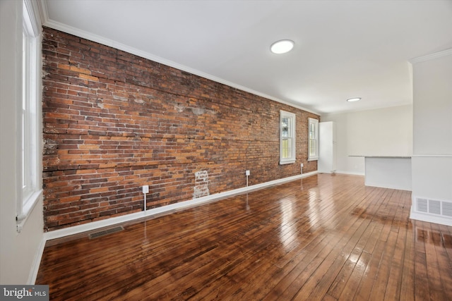 spare room with hardwood / wood-style flooring, brick wall, and crown molding