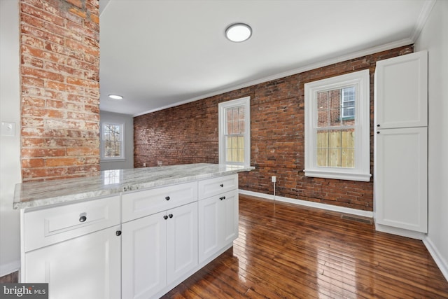 kitchen featuring white cabinetry, brick wall, a healthy amount of sunlight, and light stone counters