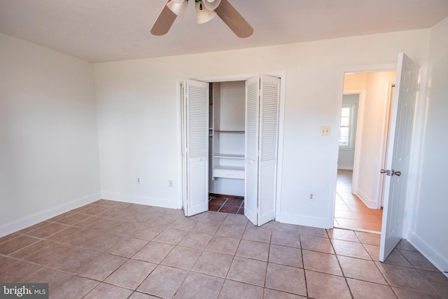 unfurnished bedroom with light tile patterned floors, a closet, baseboards, and a ceiling fan