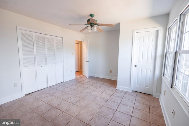 unfurnished bedroom featuring light tile patterned floors, a closet, baseboards, and ceiling fan