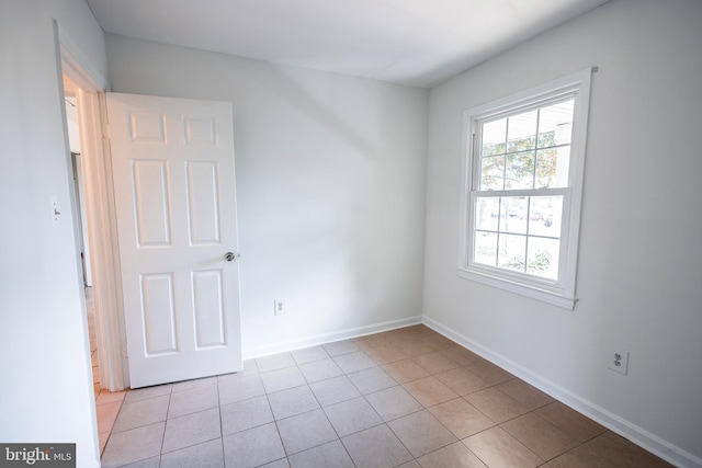 spare room with light tile patterned flooring and baseboards