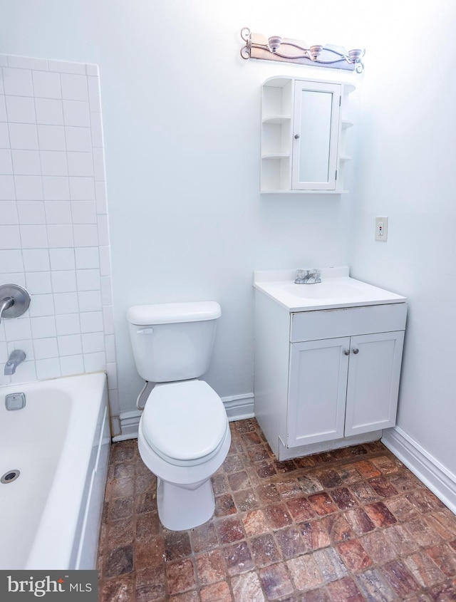 bathroom featuring vanity, toilet, baseboards, and stone finish flooring