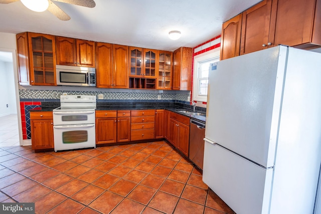 kitchen with a sink, decorative backsplash, stainless steel appliances, dark countertops, and brown cabinets