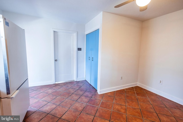 empty room featuring tile patterned floors, baseboards, and a ceiling fan