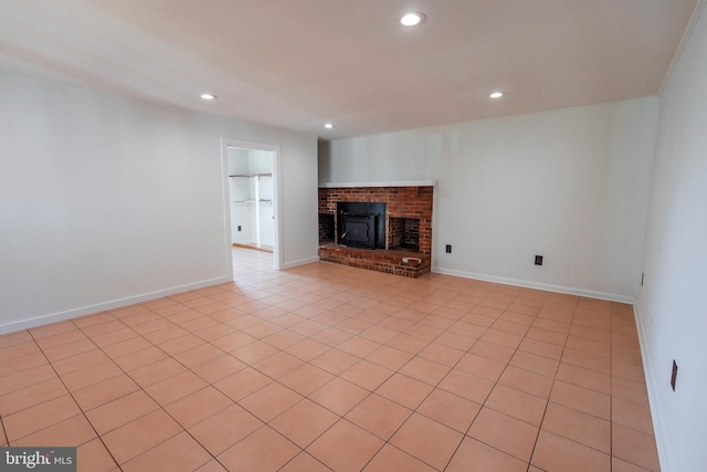 unfurnished living room with a brick fireplace, recessed lighting, and baseboards