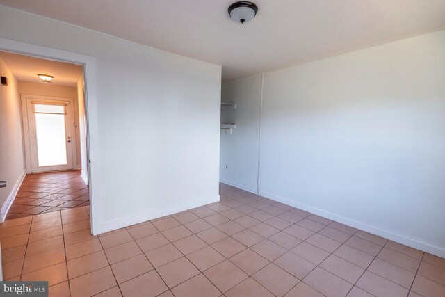 empty room with light tile patterned floors and baseboards