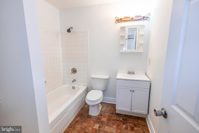 bathroom featuring toilet, stone finish flooring, shower / washtub combination, baseboards, and vanity