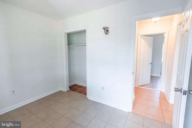 unfurnished bedroom featuring a closet, baseboards, and light tile patterned flooring