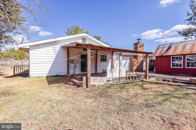 rear view of house with fence, a wooden deck, a yard, a chimney, and an outdoor structure