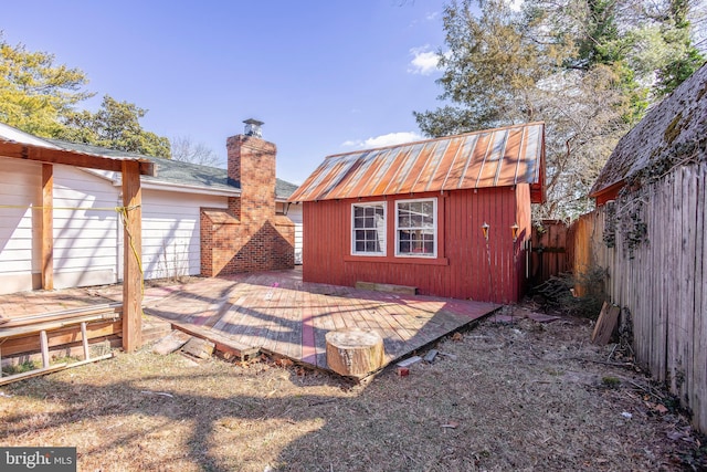 rear view of property with a storage unit, fence, an outdoor structure, a wooden deck, and a chimney