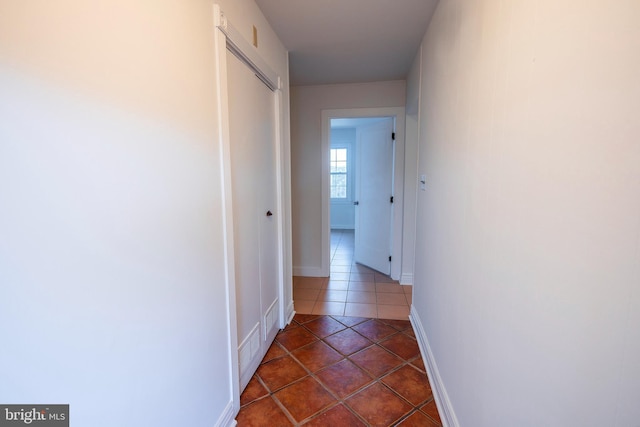 hall with baseboards and dark tile patterned flooring