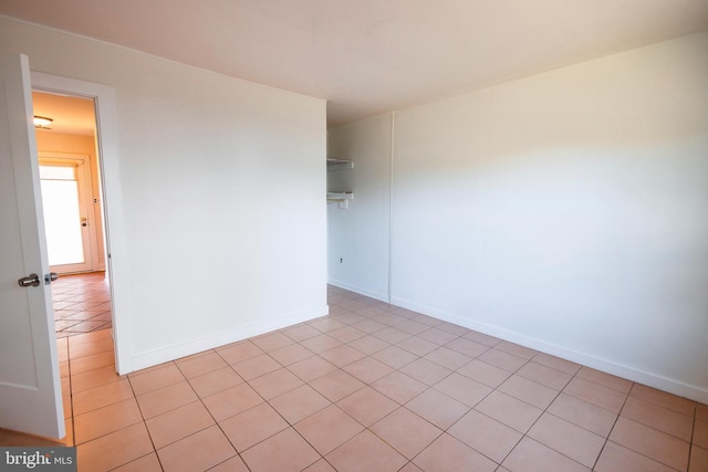 empty room with light tile patterned floors and baseboards