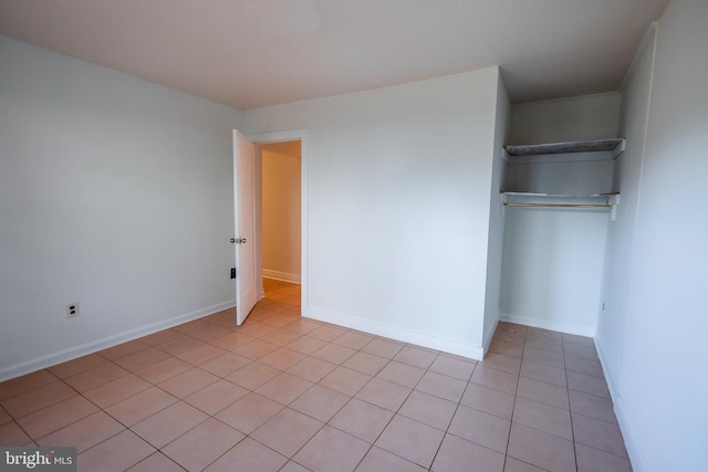 unfurnished bedroom featuring a closet, light tile patterned floors, and baseboards