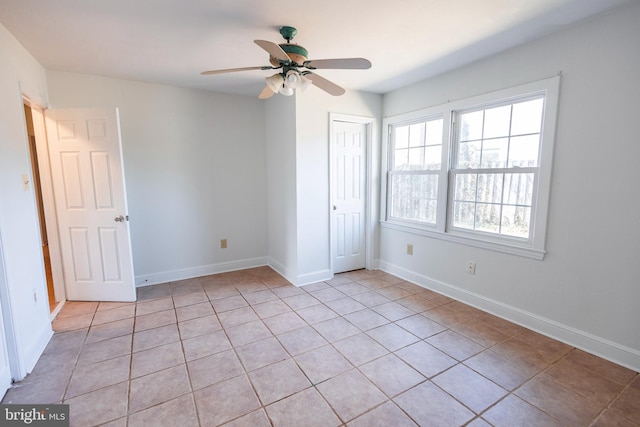 unfurnished bedroom with light tile patterned floors, baseboards, a closet, and ceiling fan