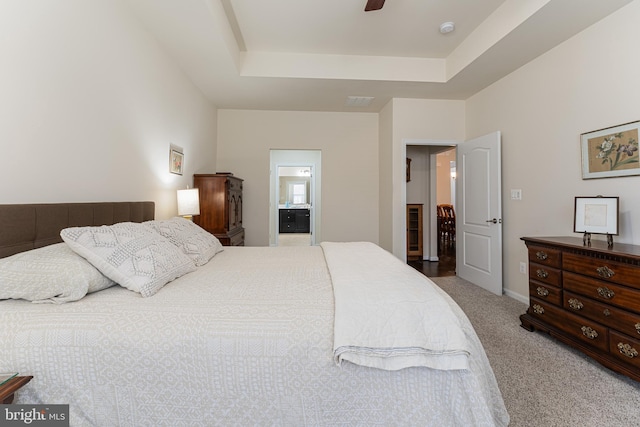 carpeted bedroom with a raised ceiling, ceiling fan, and ensuite bathroom